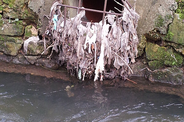 A sewage grate showing debris that has been allowed to flow into a river